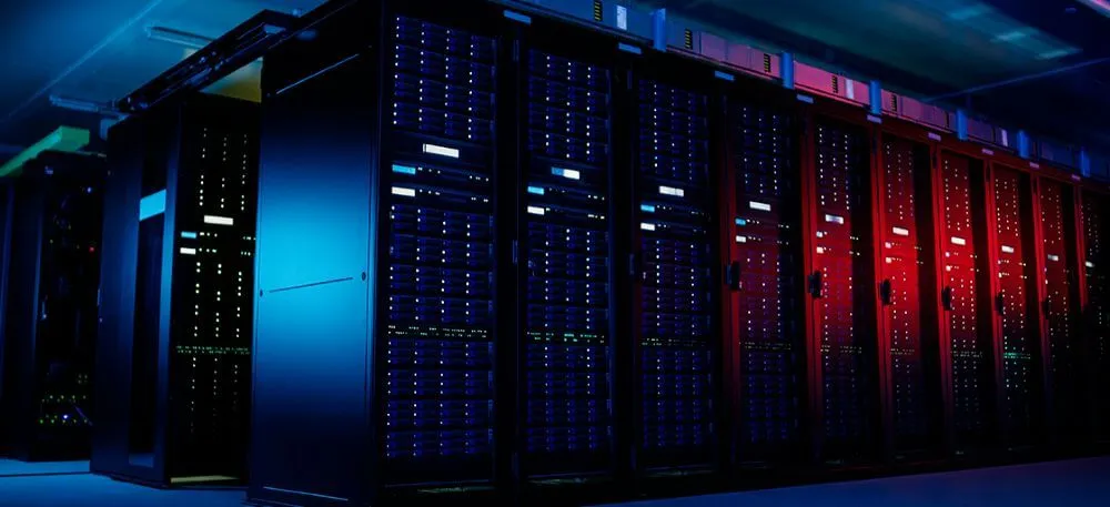 Corredor de data center com racks de servidores corporativos iluminados em azul e vermelho, ideal para otimização de TI.
